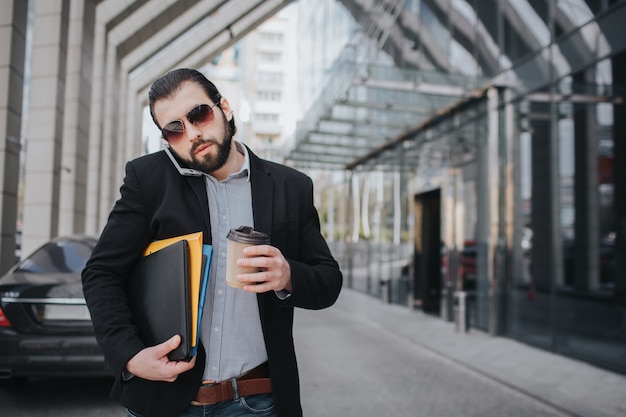 L'uomo impegnato ha fretta, non ha tempo, sta andando a mangiare uno spuntino in viaggio. Lavoratore che mangia, beve caffè, parla al telefono, allo stesso tempo. Uomo d'affari che fa più compiti.