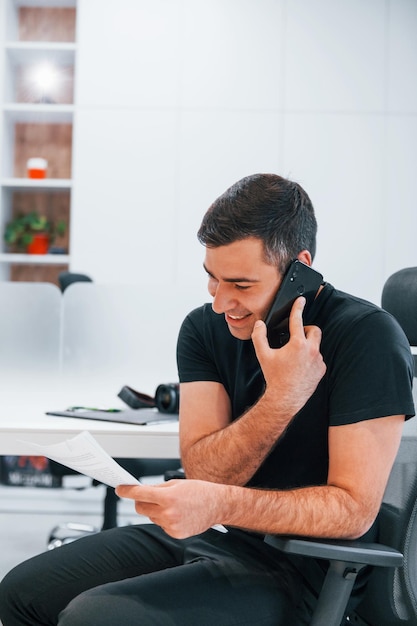 L'uomo in abiti neri ha un lavoro in ufficio seduto vicino al tavolo