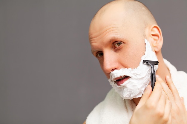 L'uomo in bagno si rade la barba con un rasoio.