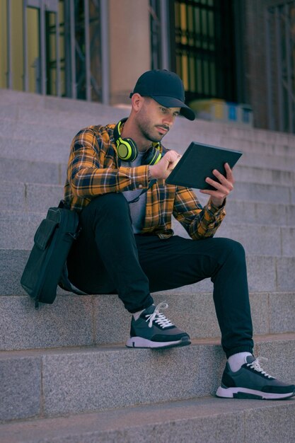 L'uomo in berretto lavora a distanza con un tablet di notte