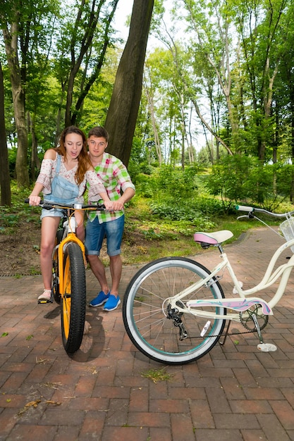 L'uomo in camicia a quadri verde e rossa insegna a una ragazza sorpresa che va in bicicletta in un parco