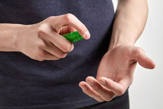 L'uomo in camicia scura sta usando spray disinfettante per le mani.