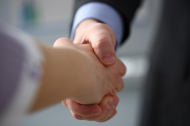 L'uomo in giacca e cravatta dà la mano come ciao in primo piano dell'ufficio.