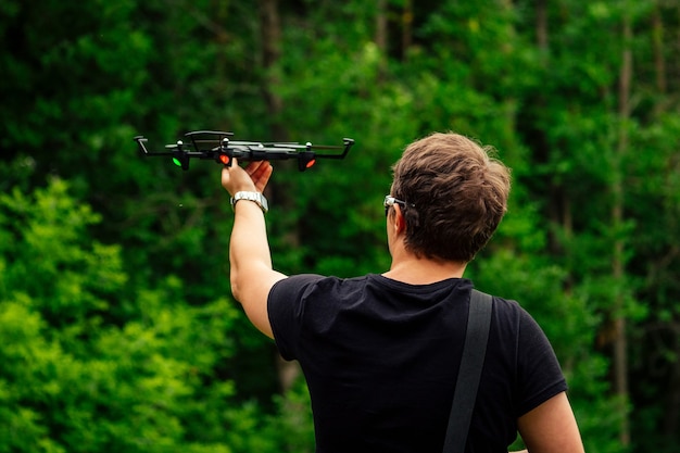 L'uomo in maglietta nera avvia un drone nel cielo della foresta