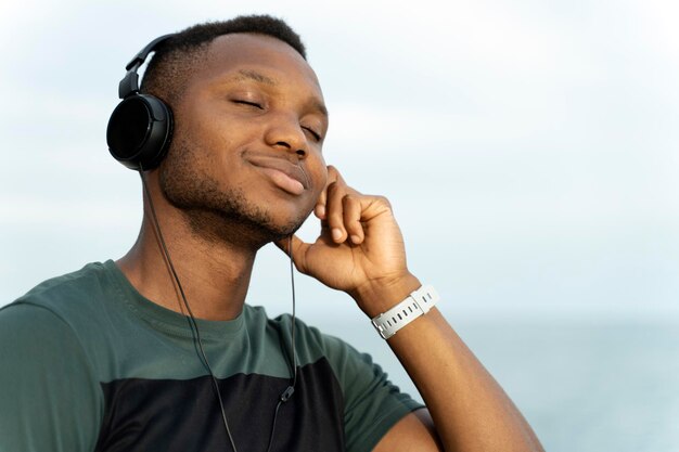 L'uomo in maglietta sportiva che ascolta musica si mette la mano sull'orecchio mentre si riposa con gli occhi chiusi