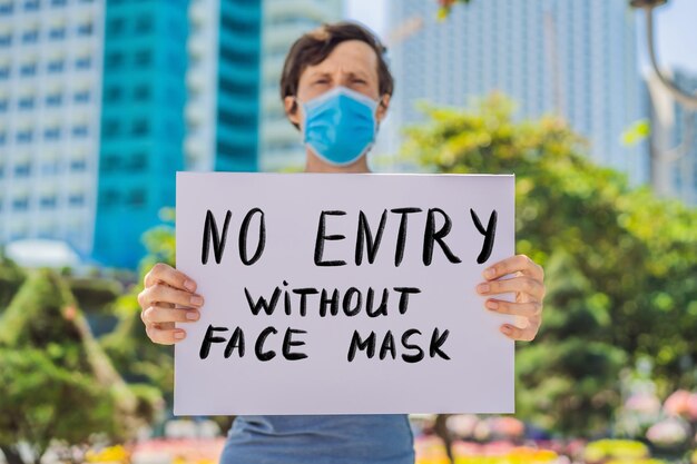 L'uomo in maschera medica previene la malattia da coronavirus tiene un poster nessuna voce senza maschera facciale mano