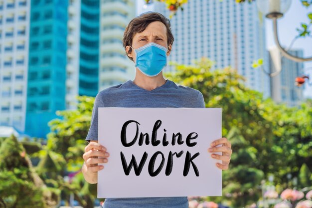 L'uomo in maschera medica previene la malattia da coronavirus tiene un testo scritto a mano di lavoro online poster