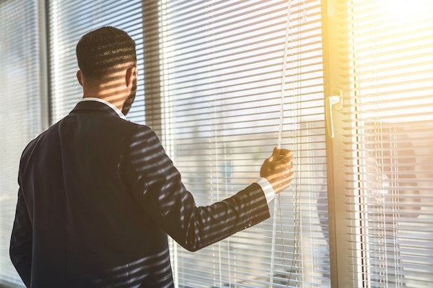 L'uomo in piedi vicino alla finestra dell'ufficio con la gelosia