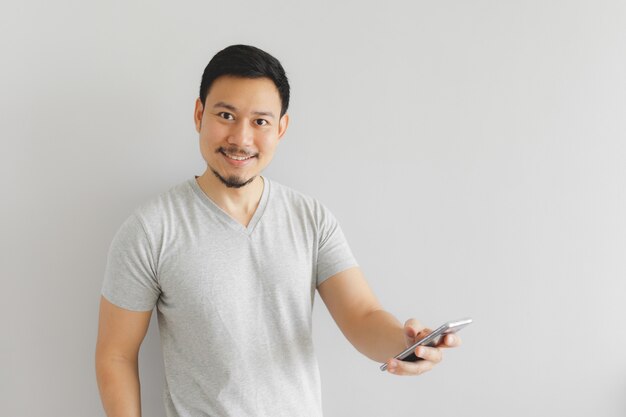 L&#39;uomo in t-shirt grigia sta usando lo smartphone.