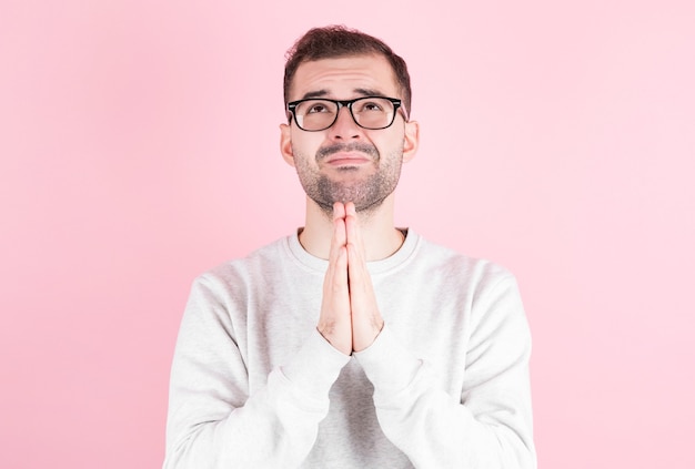 L'uomo in un maglione bianco casa esprime un desiderio per il suo compleanno su sfondo rosa.