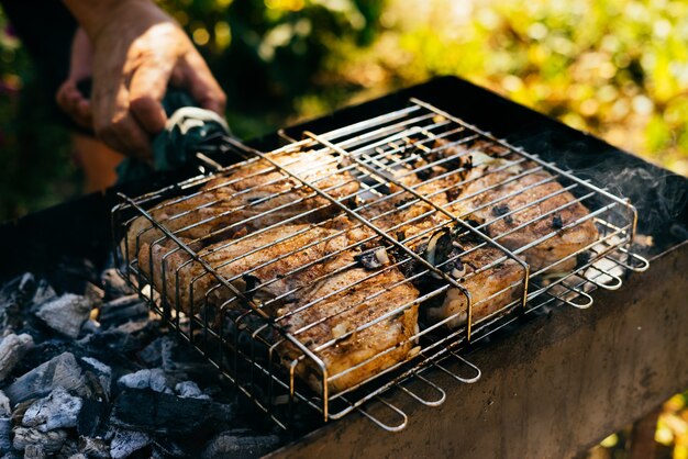 L'uomo in un picnic sulla natura cucina uno shish kebab, carne su un braciere e fuoco