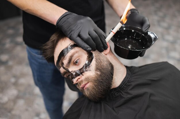 L'uomo in un salone di bellezza sta rimuovendo il cerume usando le candele