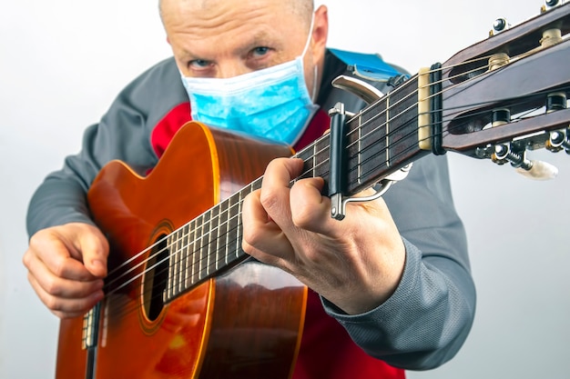 L'uomo in una mascherina medica suona la chitarra classica isolata