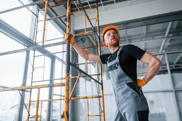 L'uomo in uniforme grigia lavora con la costruzione all'interno di un grande ufficio moderno durante il giorno