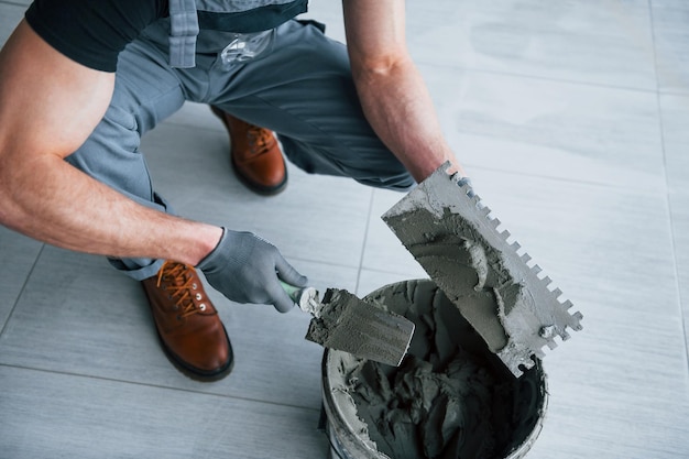 L'uomo in uniforme grigia lavora con la piastra all'interno in un grande ufficio moderno durante il giorno