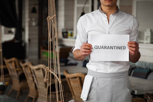 L'uomo in uniforme sta tenendo il foglio di carta bianco con la parola in quarantena