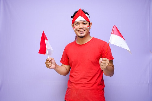 L'uomo indonesiano eccitato celebra il giorno dell'indipendenza indonesiana il 17 agosto tenendo la bandiera indonesiana