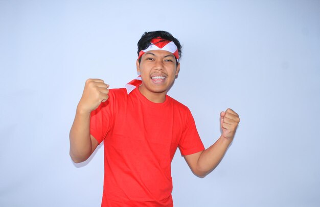 l'uomo indonesiano eccitato celebra il successo o l'obiettivo nel giorno dell'indipendenza dell'indonesia indossando una maglietta rossa