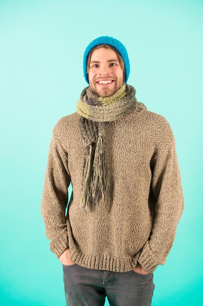 L'uomo indossa abiti a maglia sfondo turchese. Concetto di accessori invernali. Vestiti a maglia di moda invernale. Accessori in maglia come cappello e sciarpa. Uomo in berretto lavorato a maglia e sciarpa stagione della moda invernale.