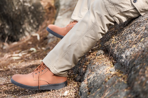 L&#39;uomo indossa pantaloni cargo marroni e seduto nel parco naturale