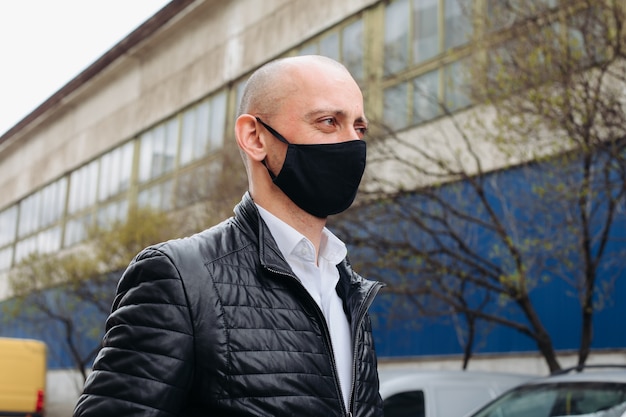 L'uomo indossa una maschera protettiva nera La maschera previene il coronavirus e l'inquinamento atmosferico da polvere Nuovo tipo di coronavirus 2019-polmonite nCoV Masked Man