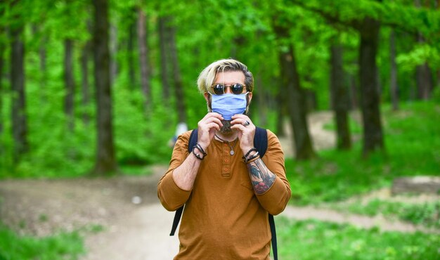 L'uomo indossa una maschera respiratoria protettiva passeggiata all'aperto in maschera medica nella foresta I metodi preventivi dalla quarantena del coronavirus del coronavirus si prendono cura della propria salute sanitaria