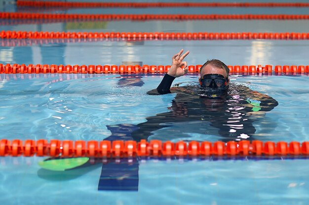 l'uomo insegna a tuffarsi in piscina, allenatore di nuoto