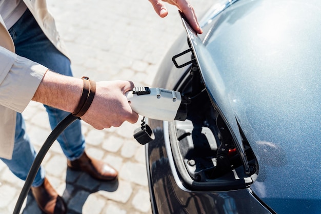 L'uomo inserisce la spina del caricabatterie nella presa dell'auto elettrica