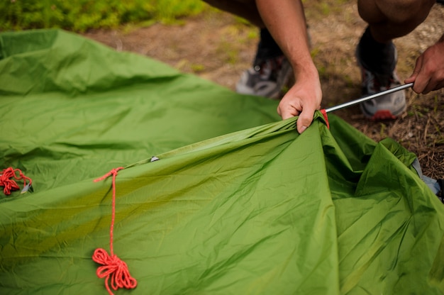 L'uomo installa una tenda verde mettendo in una struttura in metallo