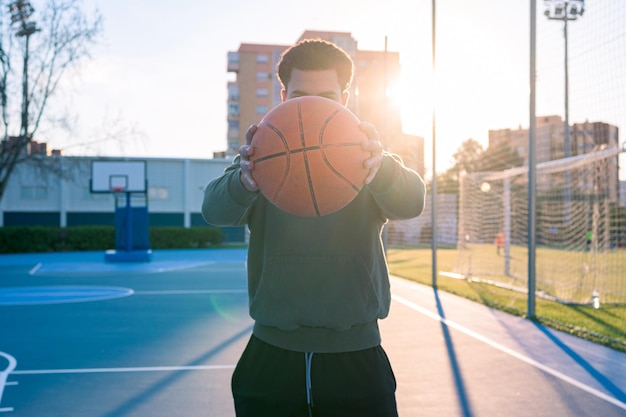 L'uomo irriconoscibile tiene una palla con le mani su un campo da basket