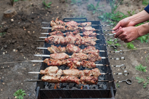 L'uomo lancia, cucina kebab alla griglia, all'aperto