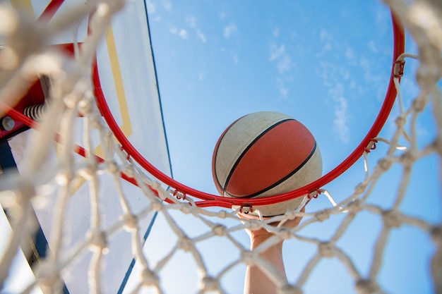 L'uomo lancia la palla nelle mani del cerchio e la schiacciata di basket nella schiacciata del canestro in movimento