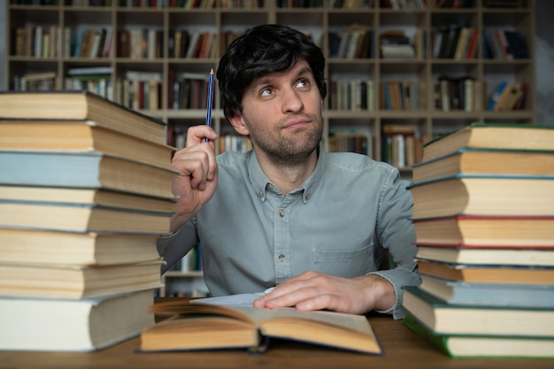 L'uomo lavora a una scrivania in biblioteca avendo una grande idea puntando il dito verso l'alto