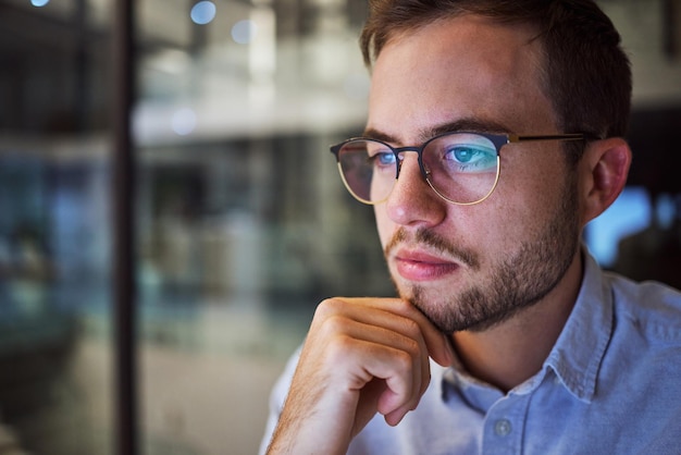 L'uomo lavora e legge con la riflessione sugli occhiali in ufficio pensando alla strategia di pianificazione per il business Uomo d'affari che lavora e schermo della tecnologia sul posto di lavoro dell'azienda o aziendale durante gli straordinari di notte