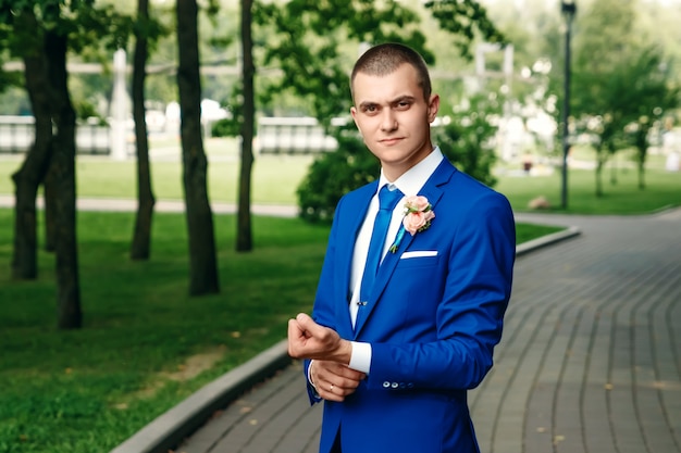 L'uomo, lo sposo in un classico abito blu su uno sfondo di natura verde. Matrimonio, sposo, creazione familiare.