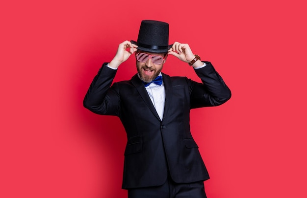 L'uomo mago indossa lo smoking divertendosi in studio mago uomo che indossa cappello a cilindro uomo mago