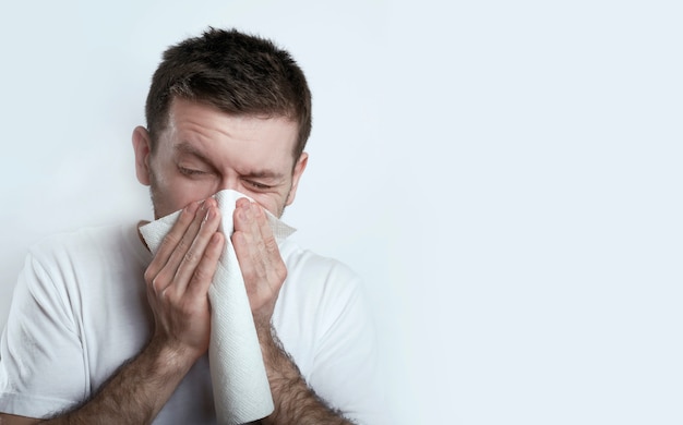 L'uomo malato starnutisce su un bianco