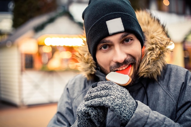 L'uomo mangia il pan di zenzero alla fiera invernale