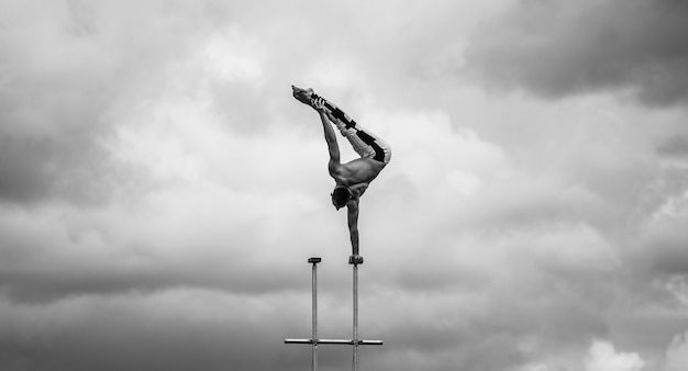 L'uomo mantiene l'equilibrio da una parte sullo sfondo del cielo nuvoloso. Concetto di yoga, meditazione e stile di vita sano.