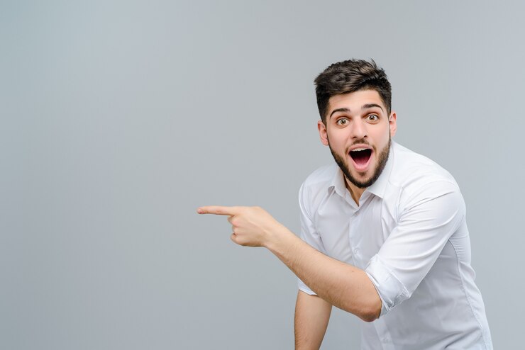 L&#39;uomo mediorientale attraente indica copyspace isolato sopra fondo grigio