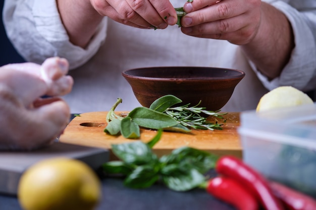 L'uomo mette la salvia in un piatto. Il processo di cottura del pollo con spezie e limone in forno.