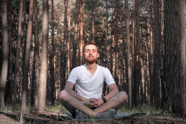 L'uomo moderno si siede nella pineta con gli occhi chiusi e gode del silenzio della natura