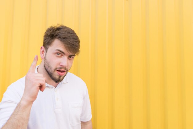 L'uomo mostra i pollici in su su una parete gialla. In un uomo con un'idea su un muro giallo.