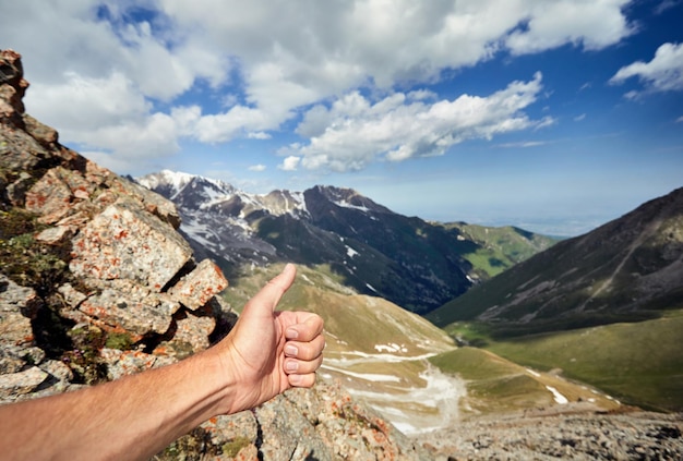 L'uomo mostra il pollice in su in montagna