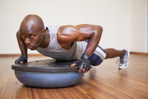 L&#39;uomo muscolare che fa spinge aumenta in palestra