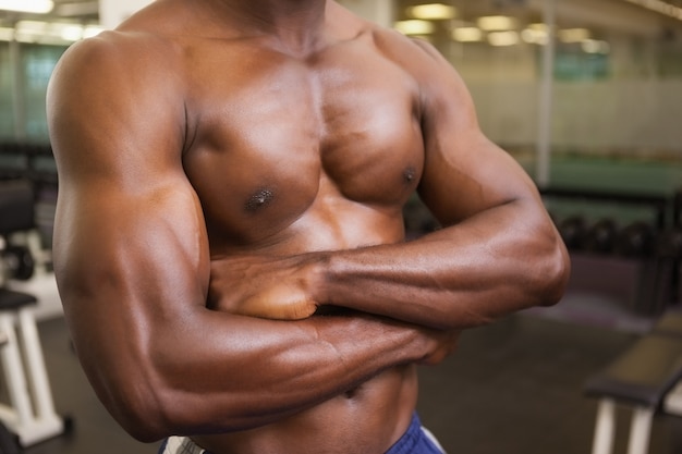 L&#39;uomo muscolare senza camicia con le armi ha attraversato in palestra