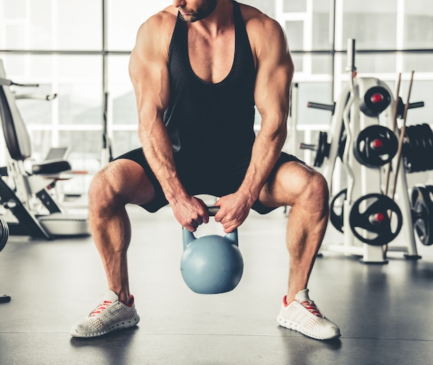 L'uomo muscolare sta risolvendo con kettlebell in palestra.