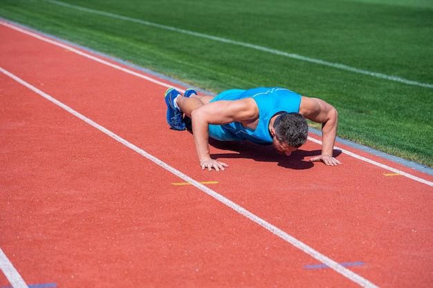 L'uomo muscoloso sta in tavola facendo push up sul successo dell'allenamento sportivo