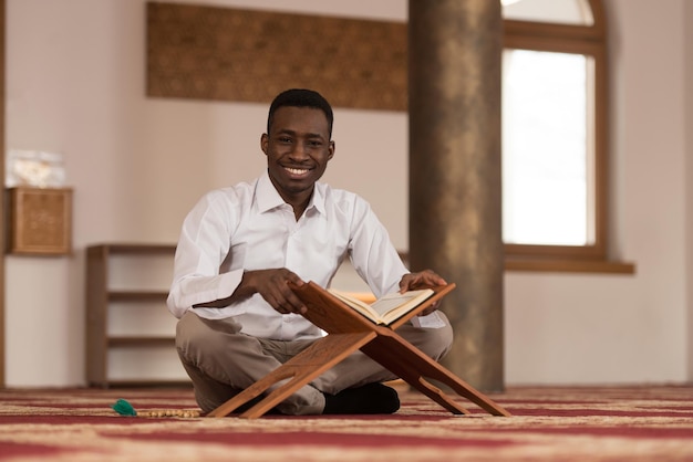 L'uomo musulmano africano nero sta leggendo il Corano