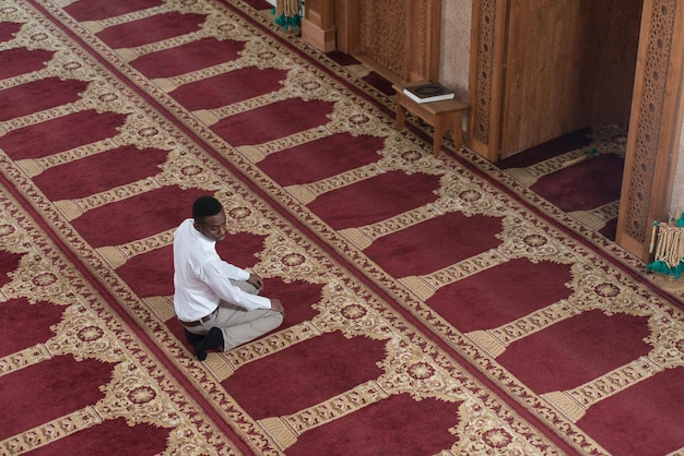L'uomo musulmano africano nero sta pregando nella moschea